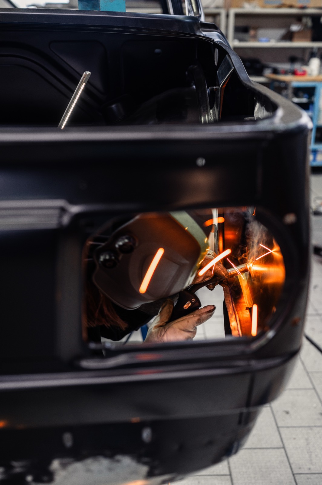 Craftsman welding BMW 2002 chassis with sparks flying