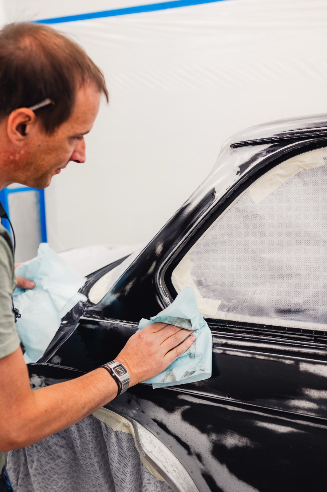 Craftsman hand-polishing black BMW 2002 body panel